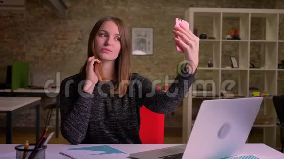 年轻的姜女在办公室背景上自拍和谈论smth视频的预览图