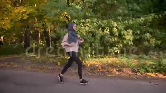 多利在秋天的森林里戴头巾跑着年轻的穆斯林女孩视频的预览图