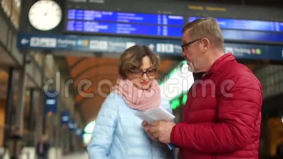 火车站的一对成熟的夫妇按时间表检查车票一个男人亲吻一个女人的额头他们就走了视频的预览图