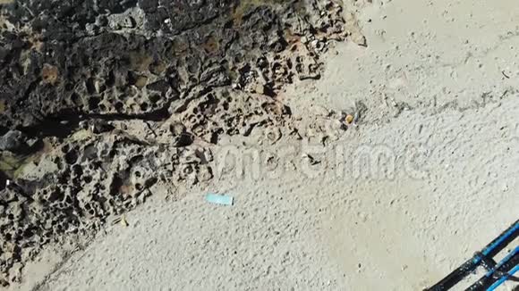 带塑料废瓶的海滩上的无人机顶景图在沙滩上用金属建筑污染的岩石海滩塑料废物视频的预览图
