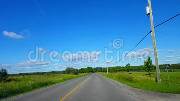 在阳光明媚的夏日里沿着农田行驶的乡村公路司机视角视野开阔美丽阳光灿烂的乡村田野视频的预览图