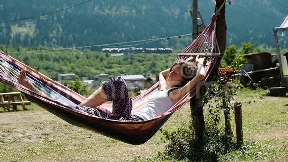 女孩睡在吊床上在青山的背景下慢动作视频的预览图