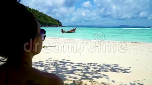 一个戴着太阳镜的女孩坐在海滩上看着大海视频的预览图