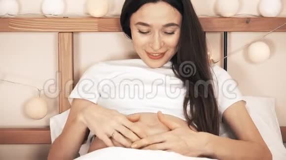 美丽的孕妇抚摸着她的肚子和她的婴儿说话视频的预览图