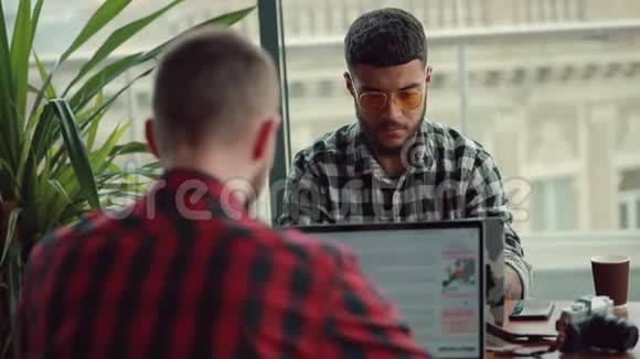 年轻人在网上写博客用手提电脑在咖啡馆做生意视频的预览图