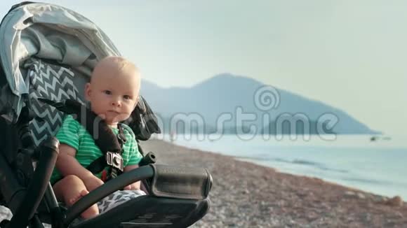 婴儿车里的孩子独自留在海滩上坐着婴儿车的小孩视频的预览图