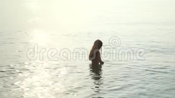 小女孩站在傍晚的海里为潜水准备的女洗面具视频的预览图