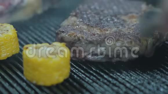 美味多汁的牛肉牛排躺在烤架表面玉米接近准备两块生肉视频的预览图