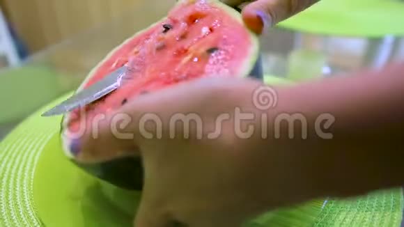 年轻漂亮的女人在桌子上用刀切西瓜视频的预览图