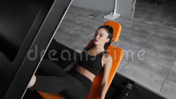 运动的年轻亚洲妇女正在研制一个模拟器用于锻炼腿部肌肉健身房的体育锻炼视频的预览图