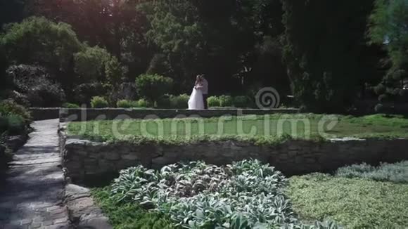 浪漫的婚礼情侣在公园里新婚夫妇牵手散步视频的预览图