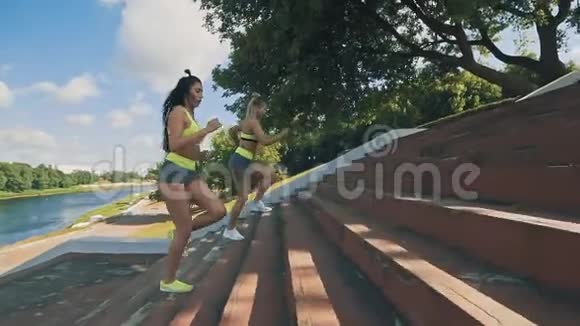 两个女人在楼上慢跑两个穿运动服的跑步者爬楼梯视频的预览图
