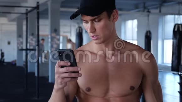 运动员在锻炼时检查智能手机年轻人在健身房锻炼时打字休息视频的预览图