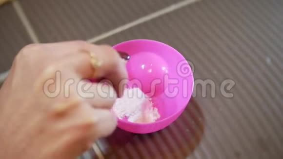 4K皮肤护理概念女人手在粉红色的杯子里为海藻酸钠面膜倒粉特写视频的预览图