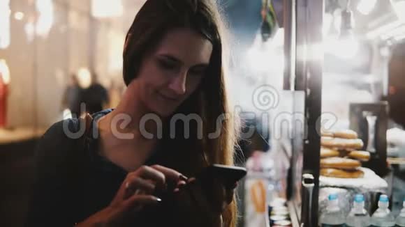 一位美丽的欧洲女商人在纽约市热气腾腾的街头食品卡车附近使用智能手机信使应用程序视频的预览图