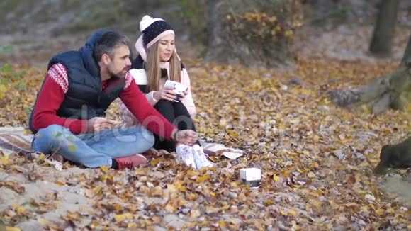海滩上的一对年轻夫妇用中国食物喂狗沙子黄色的叶子秋天4K慢莫视频的预览图
