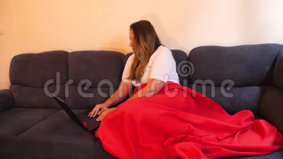 女性数字游牧民在客厅的沙发上用笔记本电脑工作视频的预览图