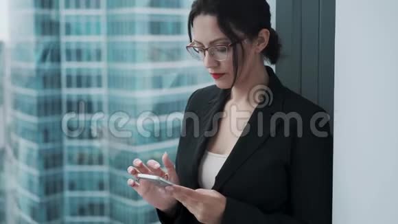 一位年轻女商人手里拿着手机的肖像这个女孩正在专心地使用智能手机视频的预览图
