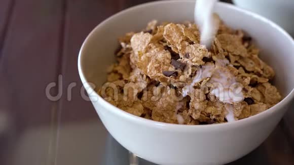 美味的早餐牛奶倒入一个碗里里面有玉米片和巧克力片视频的预览图