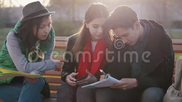 三个亚洲青少年在日落时在公园做作业视频的预览图