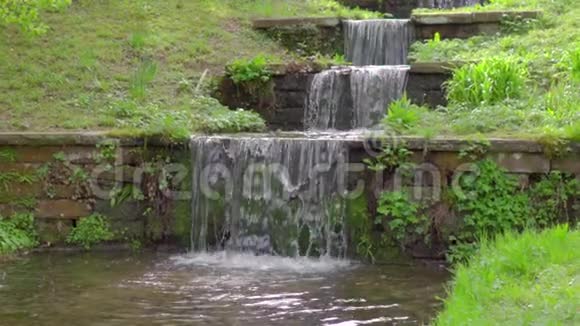 美丽的阶梯瀑布泉水清澈的水流穿过石阶在绿草和植物之间缓慢流动视频的预览图