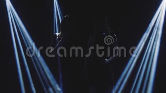 两个歌手在烟雾和蓝光唱成复古麦克风和舞蹈黑色背景剪影视频的预览图
