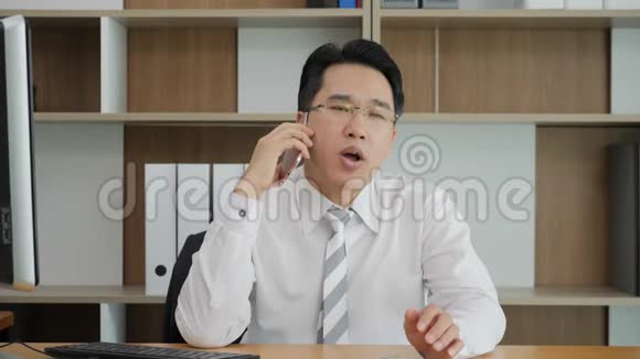 年轻的亚洲商人在办公室用手机聊天视频的预览图