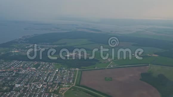 从飞机窗口在薄雾中俯瞰沿海城镇田野和海洋视频的预览图