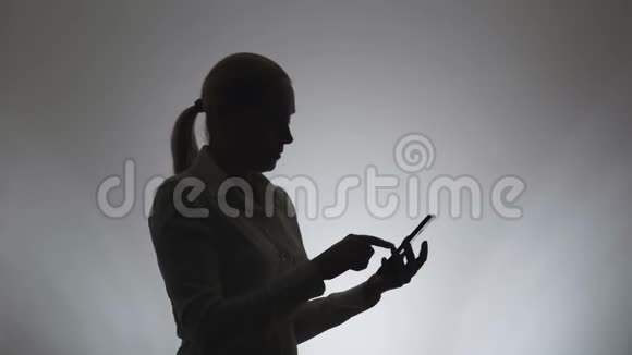 白色背景的女人的剪影一个女人在电话里写信息女人用互联网视频的预览图