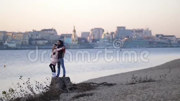 快乐的男人和女孩拥抱并在远处观看相握双手微笑秋天的海滩视频的预览图