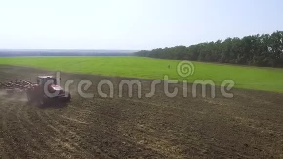 早春红色拖拉机耕土的空中作业视频的预览图