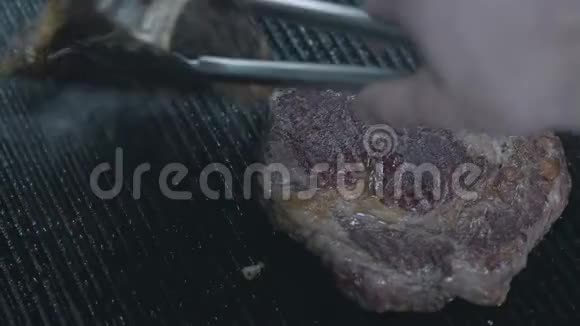 将餐厅厨房里的两块生肉烹制起来厨师用钳子换肉厨师在准备视频的预览图