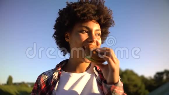 可爱的卷发女士在户外享用美味的汉堡脂肪零食和快餐视频的预览图