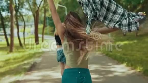 穿短裤的漂亮时髦女人在公园里跑步年轻女孩在户外玩得很开心视频的预览图