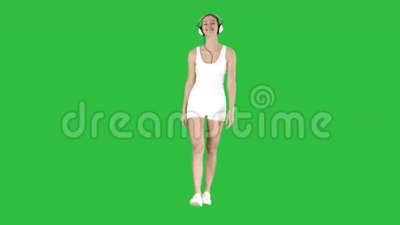 迷人的健身女孩在绿色屏幕上散步和听音乐Chroma键视频的预览图