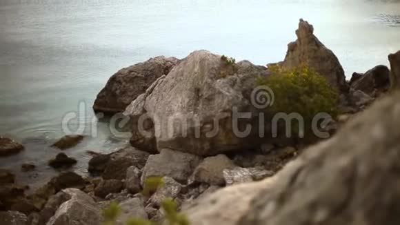 美丽平静的岩石海线和悬崖之间的小岩石海滩海滩上的空充气船视频的预览图