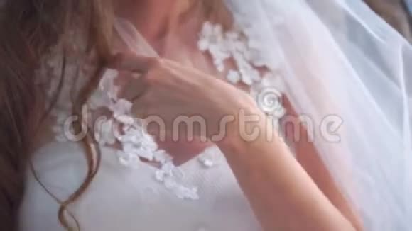 年轻的新娘穿着白色的婚纱手握着礼服的装饰细节和鲜花的装饰视频的预览图