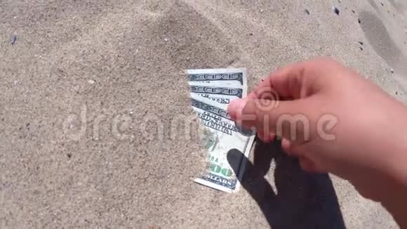 一个女孩从沙子里拿出三百美元的钞票视频的预览图