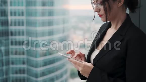 穿商务服的年轻女性使用智能手机摩天大楼背景下的商业女性肖像视频的预览图