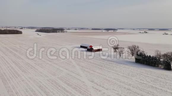 空中飞越白雪覆盖的乡村景观典型的美国农场和木制红色谷仓视频的预览图