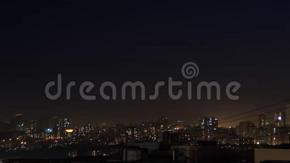 夜间城市天际线时间流逝从塔楼屋顶俯瞰现代城市的全景窗户里灯光闪烁相机移动视频的预览图
