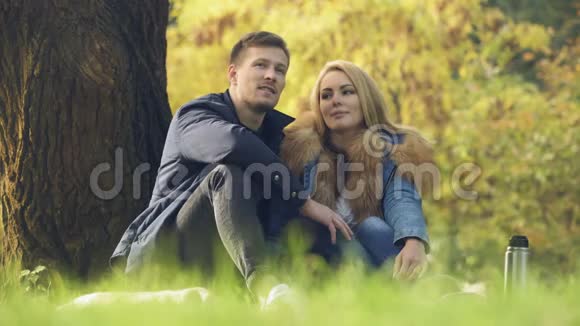 爱的夫妇坐在树下在户外约会在公园里野餐视频的预览图