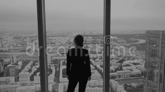 一个商人靠在摩天大楼窗户上的剪影视频的预览图