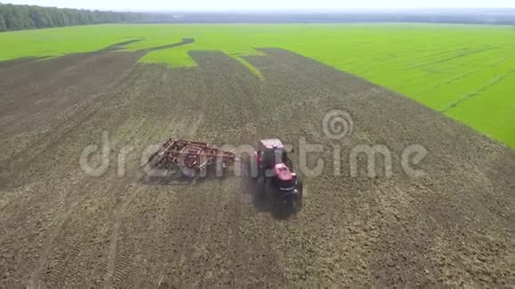 红色拖拉机在农田耕地上旋转的空中视频的预览图