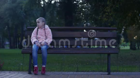 可怜的女孩坐在公园的长凳上失去了失踪的孩子等待父母视频的预览图