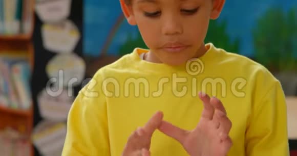 非裔美国小学生用手指在学校教室里的桌子旁数数的前景视频的预览图
