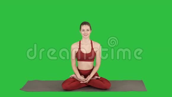 美丽的年轻女子坐在瑜伽姿势莲花改变位置她的手在绿色屏幕Chroma键视频的预览图