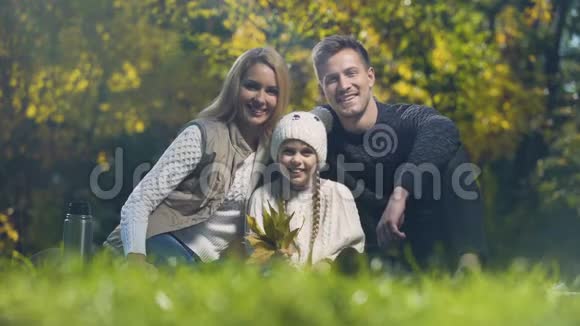 家人微笑着在秋天公园野餐做父母视频的预览图