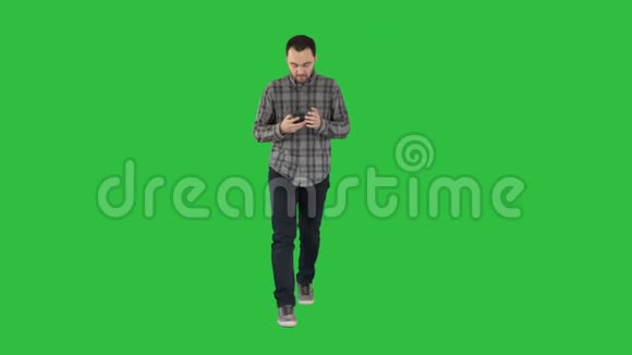 一个拿着手机在绿色屏幕上阅读信息的年轻人手上拿着彩色键视频的预览图