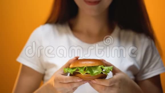 对着镜头展示牛肉汉堡的女孩被快餐诱惑不健康的饮食视频的预览图